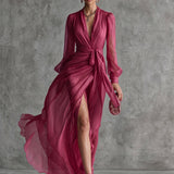 Elegante vestido largo de mujer en gasa rosa perla con escote en V y cinturón en la cintura.